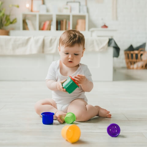Baby girl sitting on the floor and playing with toys.