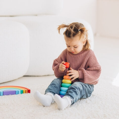Cute girl playing with colorful stacking toys.