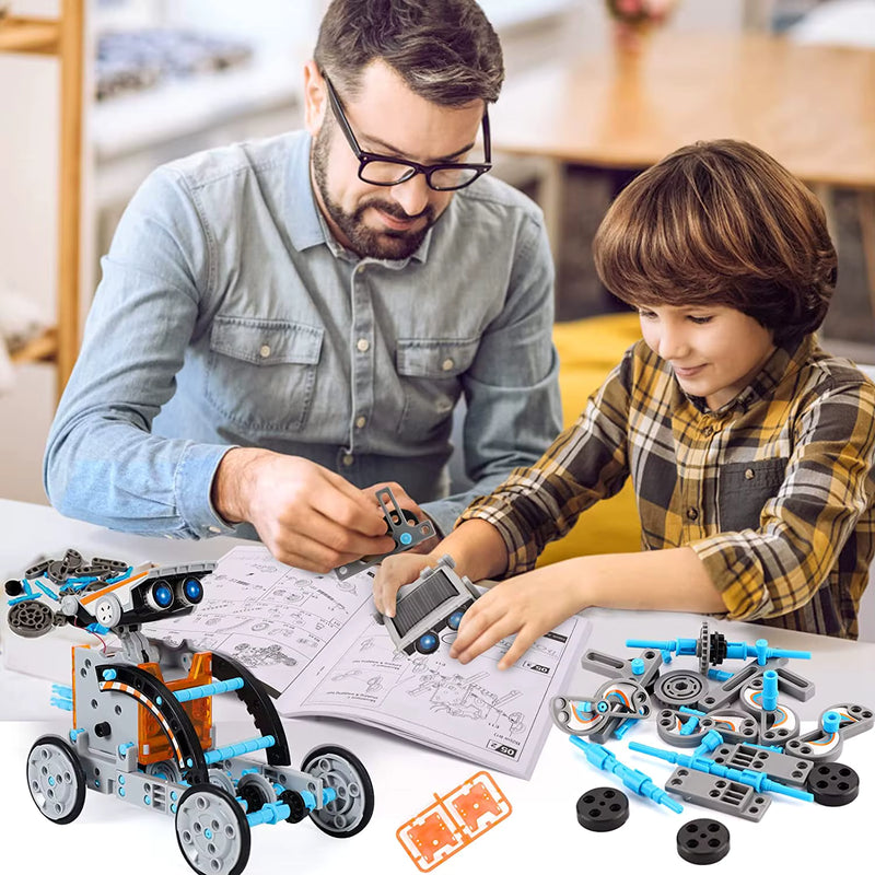 Adult and child building a STEM robot kit together at a table, with instruction booklet, toy parts, and a partially assembled wheeled robot.