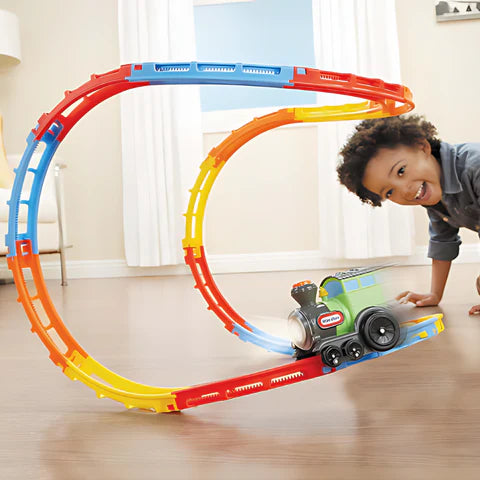 Little boy playing with a toy train that is running on circular tracks.