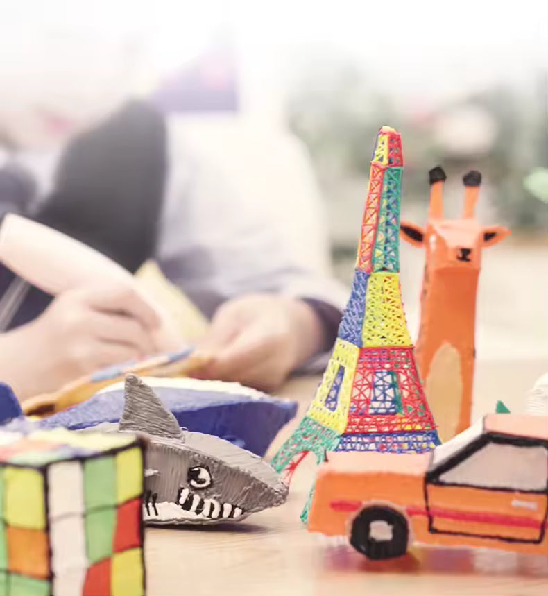 Colorful designs like a car, shark, Eiffel tower made by a 3D Pen toy.