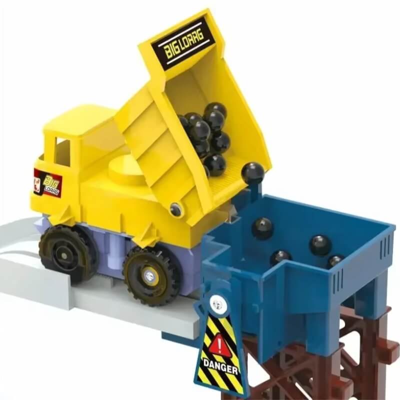 A yellow toy dump truck labeled "BIGLORAG" tipping black balls into a blue container with a "DANGER" sign, part of a construction-themed playset.