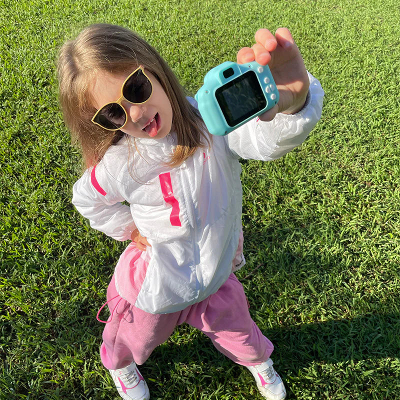 Little girl taking a selfie with a blue camera.