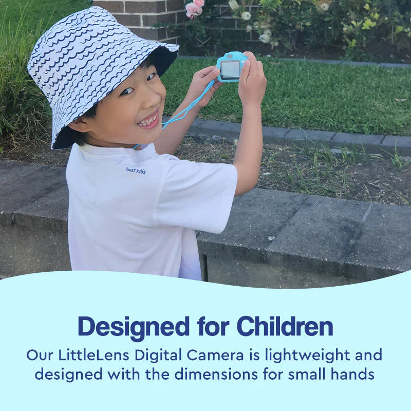 Boy smiling while taking a photo with his blue little camera.