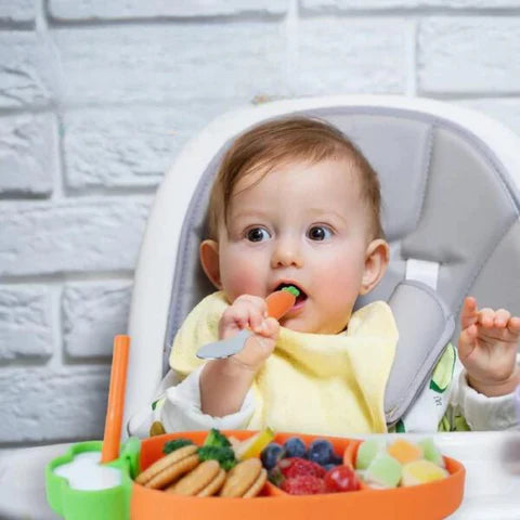 Baby eating healthy snacks from his carrot shaped silicone dining set by Smartoon Kids.