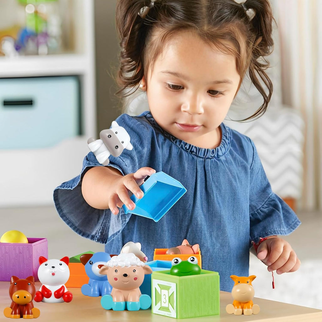 Girl playing with colorful farm animals which color-respond to matching little houses with numbers on them. 