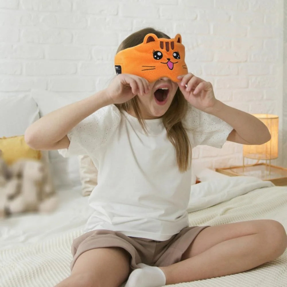 Little girl yawning and getting ready to sleep on the bed while putting on her SnuggleSounds with Cat design. 