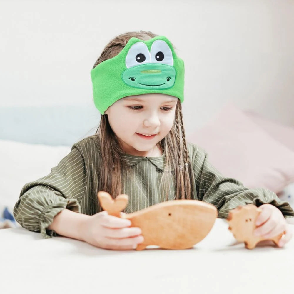 Girl playing with wooden animals while wearing Crocodile SnuggleSounds headphones.